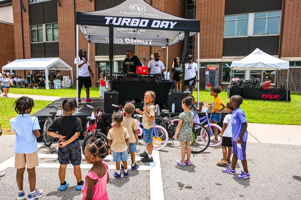 Kids gathered by the DJ and rows of bikes at the Turbo Day 2026 bike giveaway