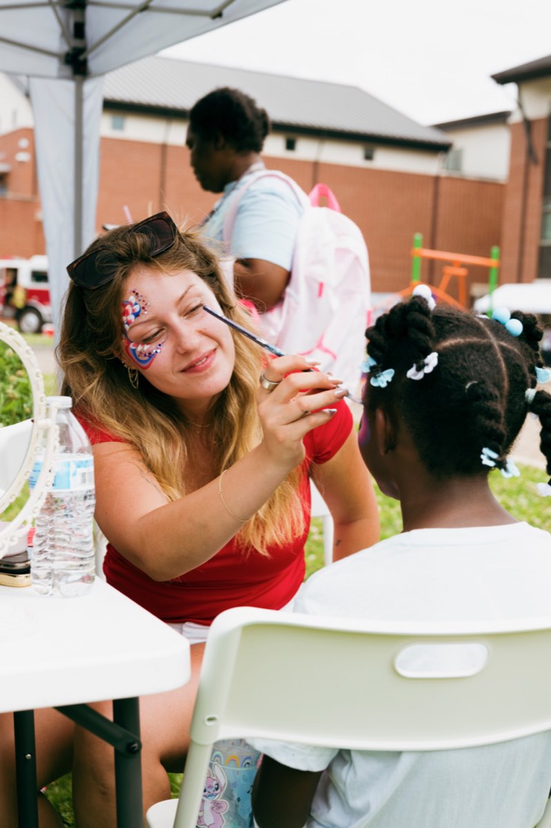 Volunteer giving a girl patriotic face paint at Turbo Day 2026