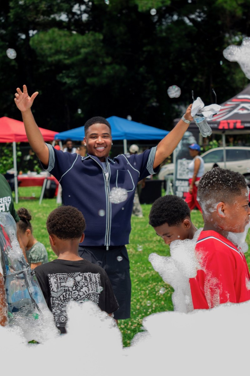 Turbo with his arms raised as kids play in the foam party at Turbo Day 2026