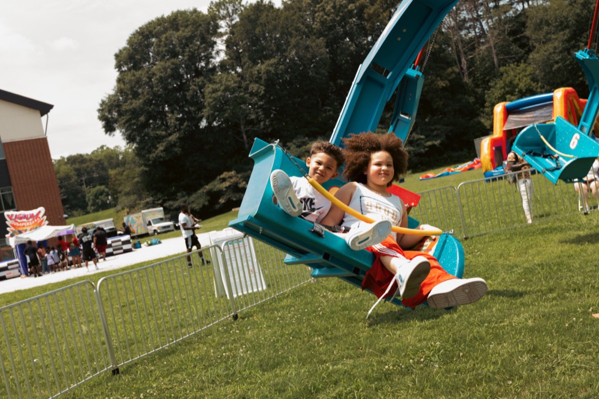 Two kids soaring on the glider carnival ride at Turbo Day 2026