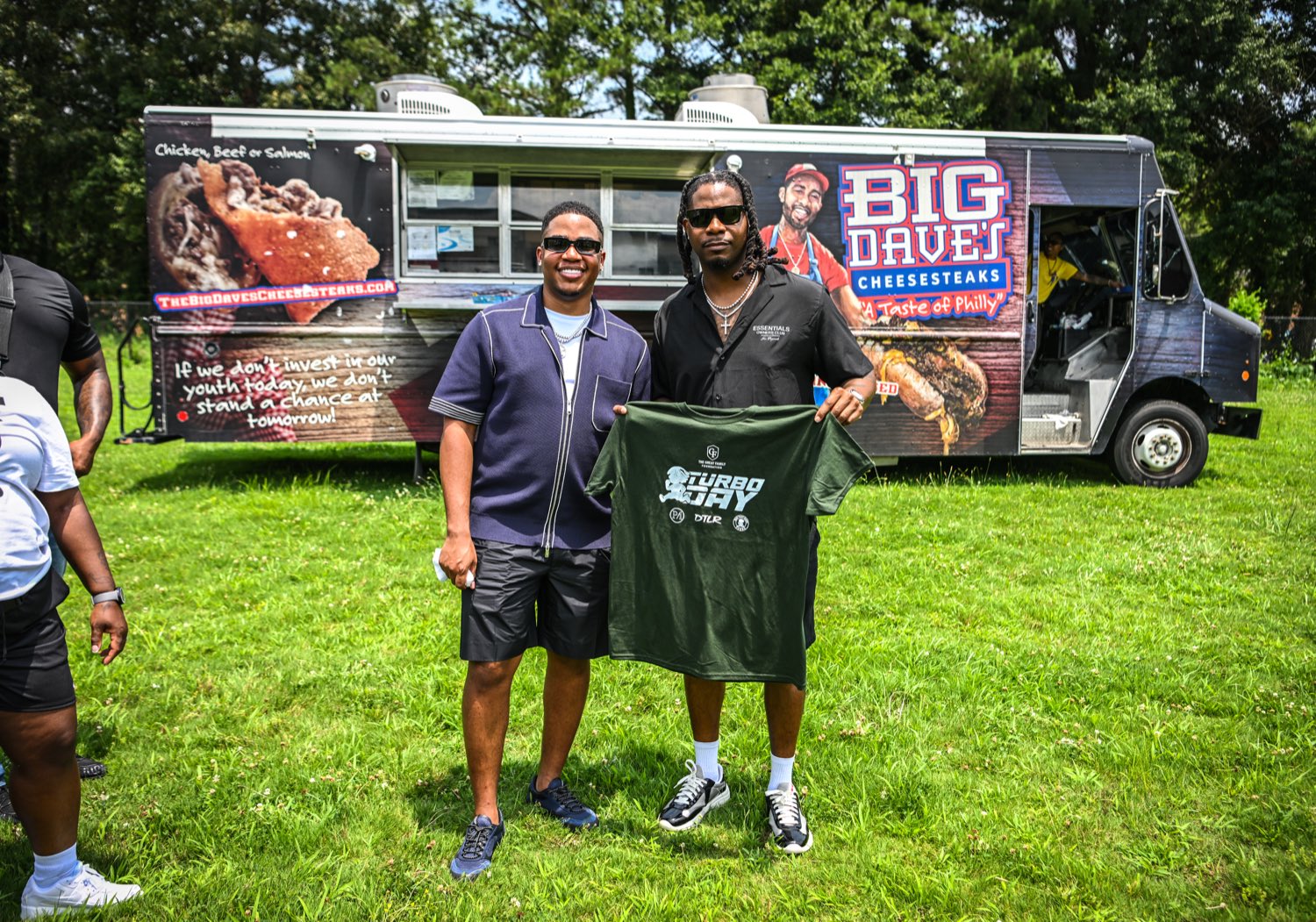 Turbo and longtime friend KV holding a Turbo Day shirt by the Big Dave's Cheesesteaks food truck